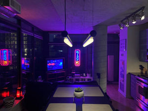 A modern apartment interior at night, illuminated by various neon signs and ambient lighting.